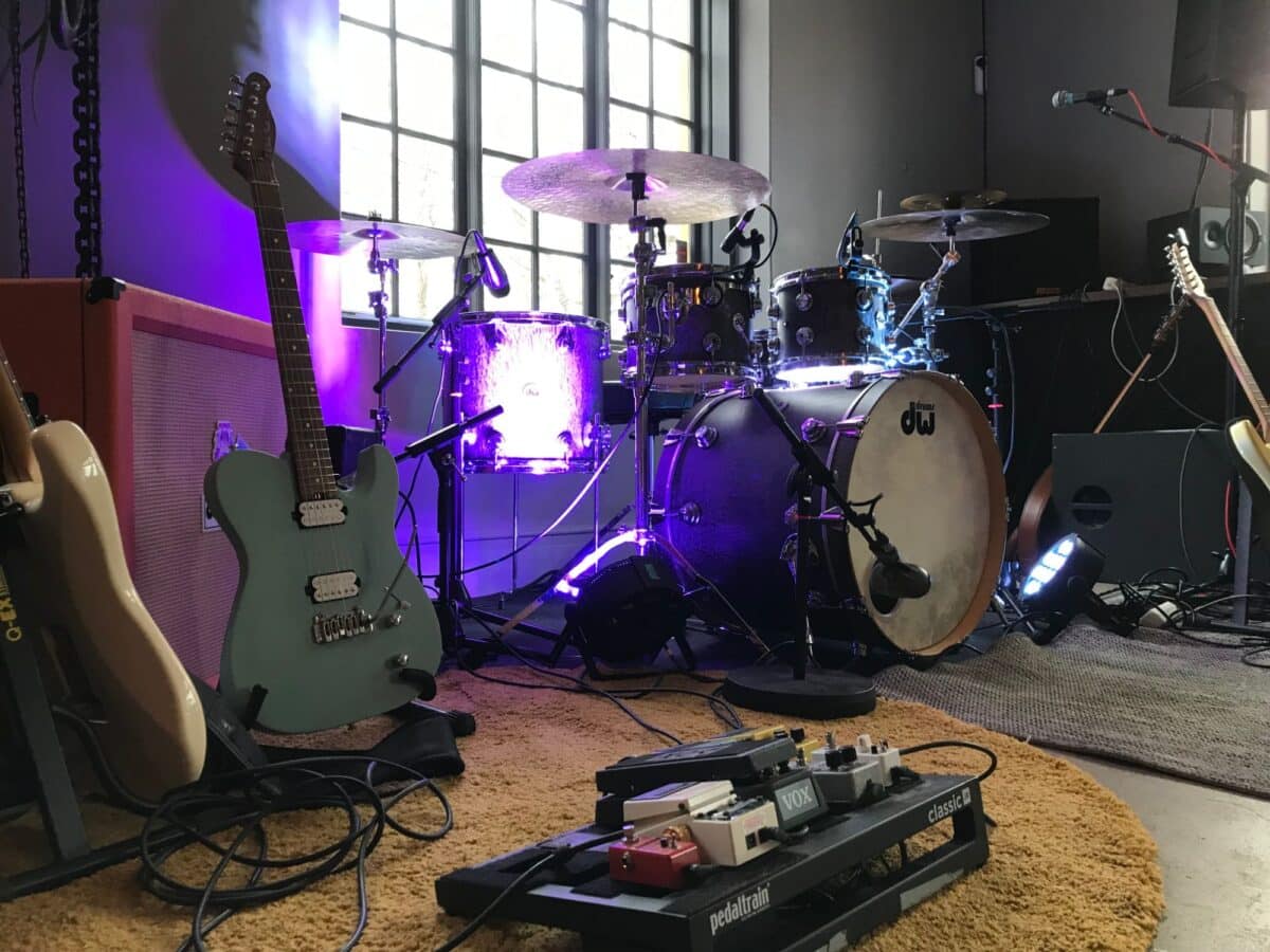 Husbandets trummor och gitarrer på Gnistans scen i lila ljus